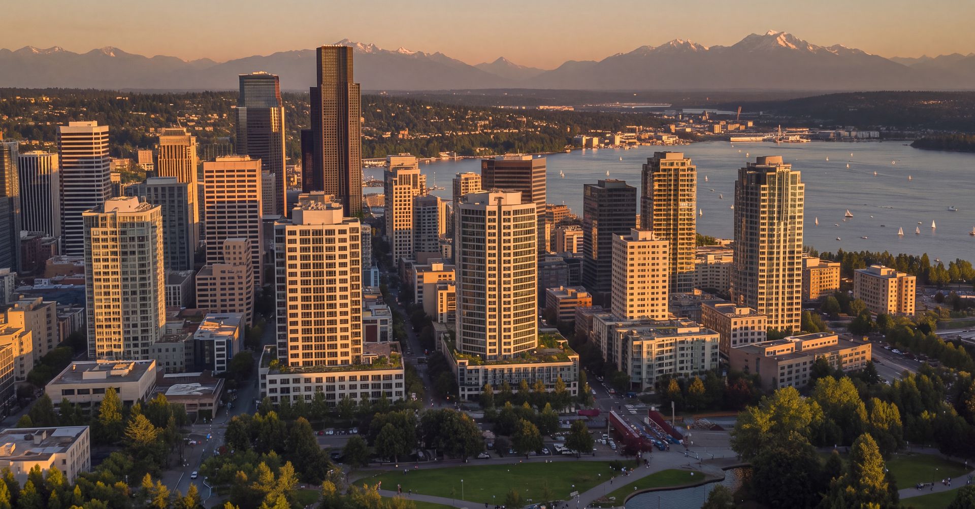 Glass office towers rising above Meydenbauer Bay in Bellevue, Washington, with Lake Washington and evergreen trees in soft Pacific Northwest light