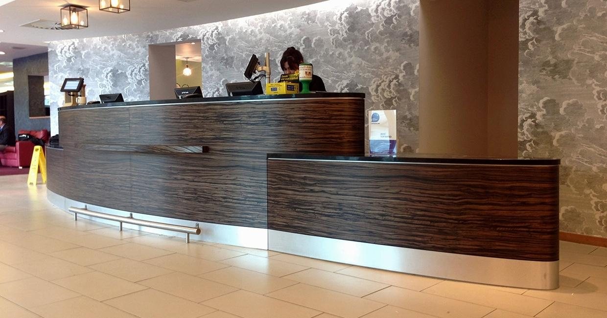Hotel reception desk with curved walnut DI-NOC face